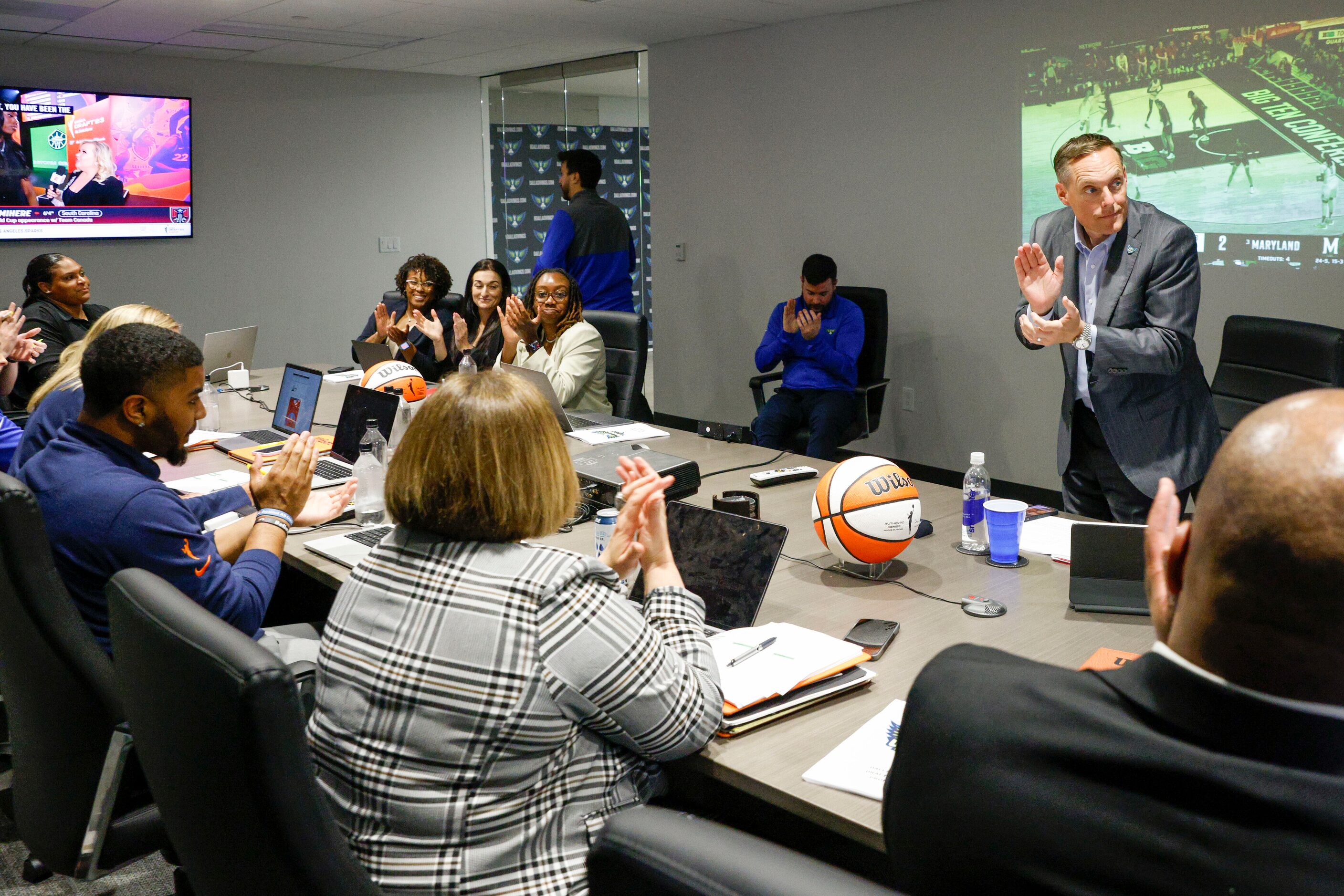 Dallas Wings President and CEO Greg Bibb (right) and members of the coaching staff applaud...