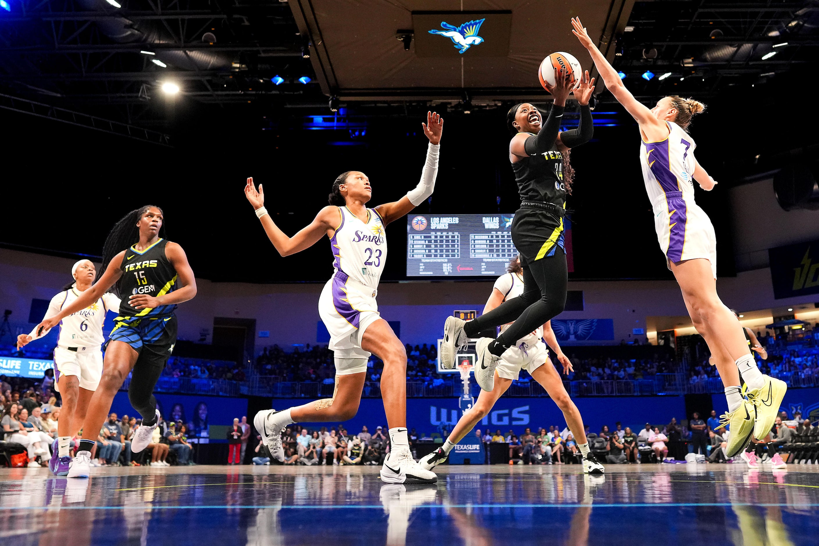 Dallas Wings guard Arike Ogunbowale (24) scores between Los Angeles Sparks forward Azura...