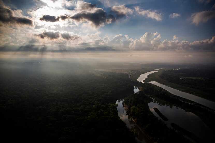 The Trinity River reflects the sun through the clouds over the Great Trinity Forest.