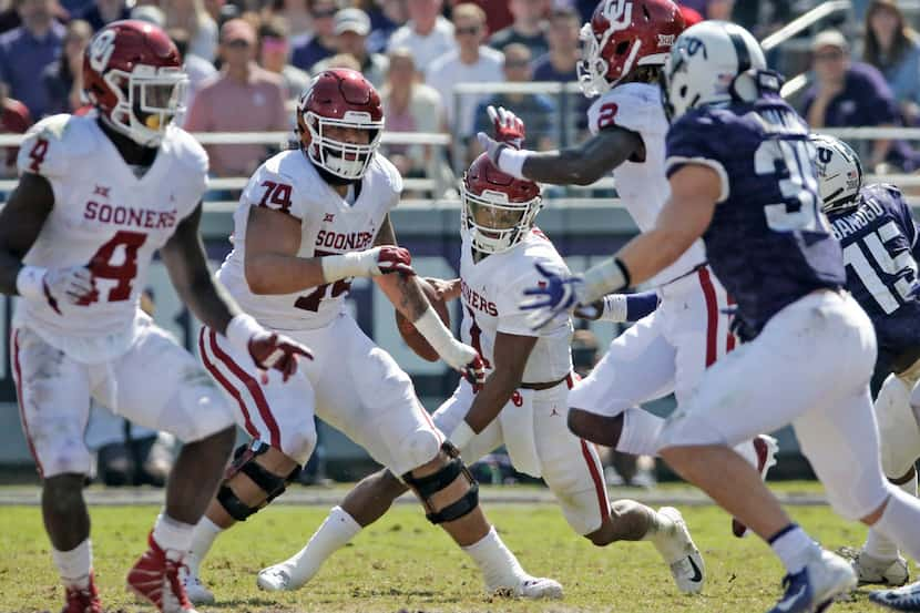 Oklahoma Sooners quarterback Kyler Murray (1) is dwarfed by teammates and opponents as he...