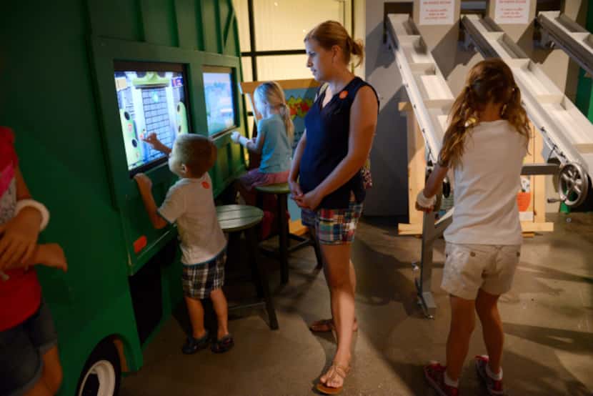 Lauren Del Busto watches her son Marcus play with a display at the recycling exhibit at the...