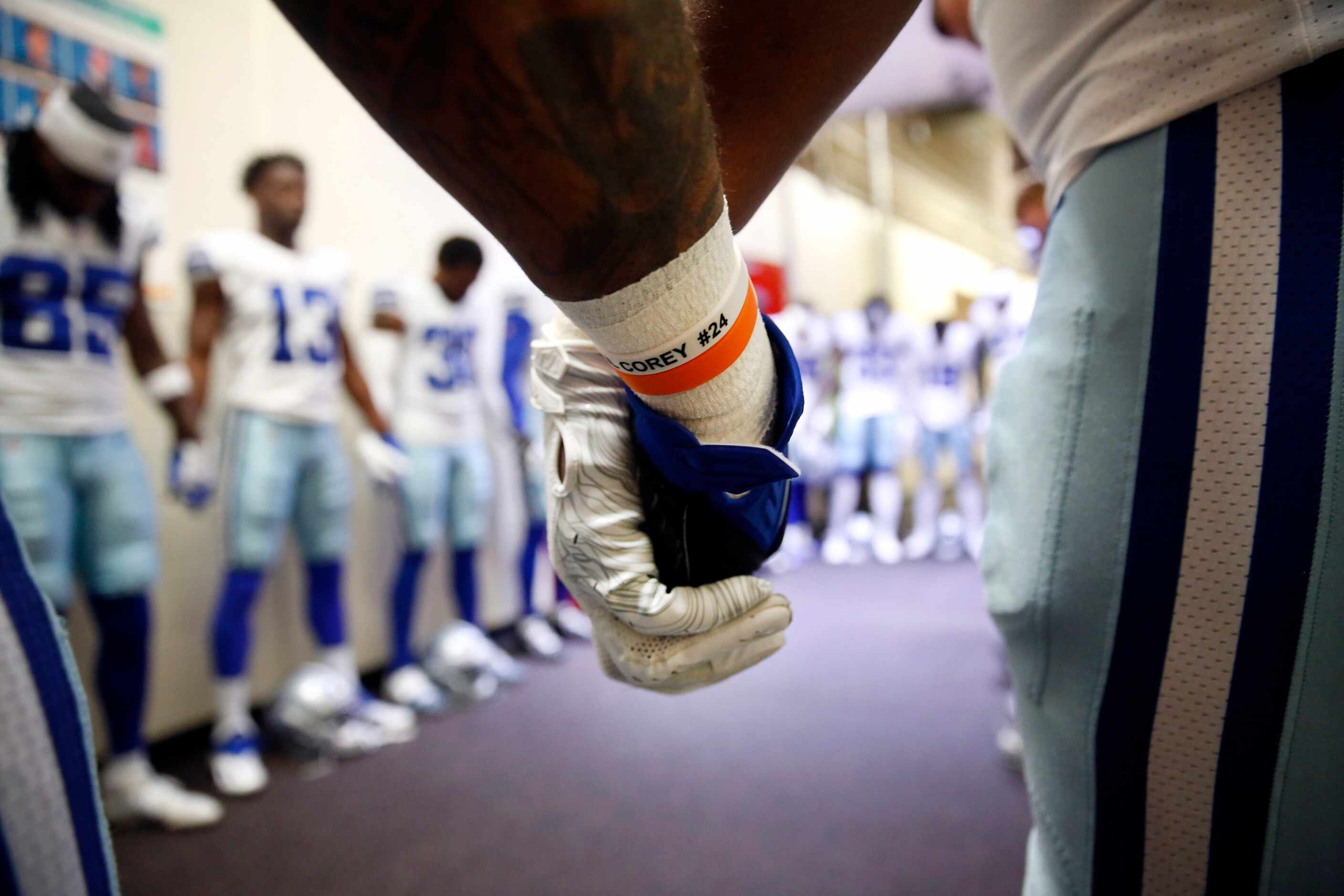 Dallas Cowboys running back Ezekiel Elliott (blue glove) joins hands with teammates as they...