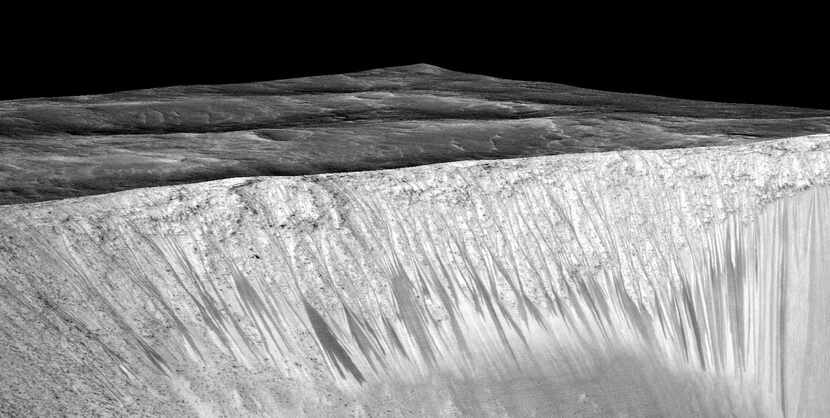 An image captured  by NASA’s Mars Reconnaissance Orbiter shows dark, narrow streaks on the...