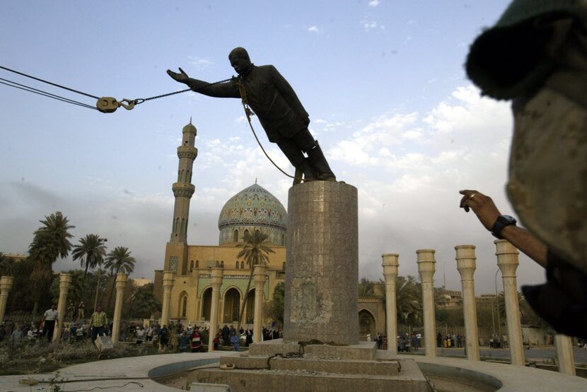 A U.S. Marine watches a statue of Saddam Hussein being toppled in Firdaus Square in downtown...