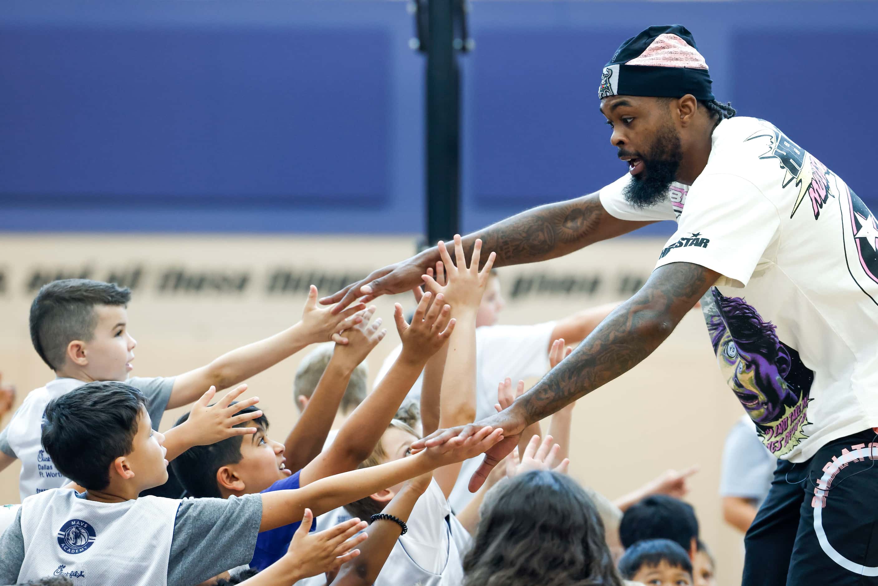 Dallas Mavericks’ Naji Marshall, hi-fives young basketball campers during a Hoop Camp,...