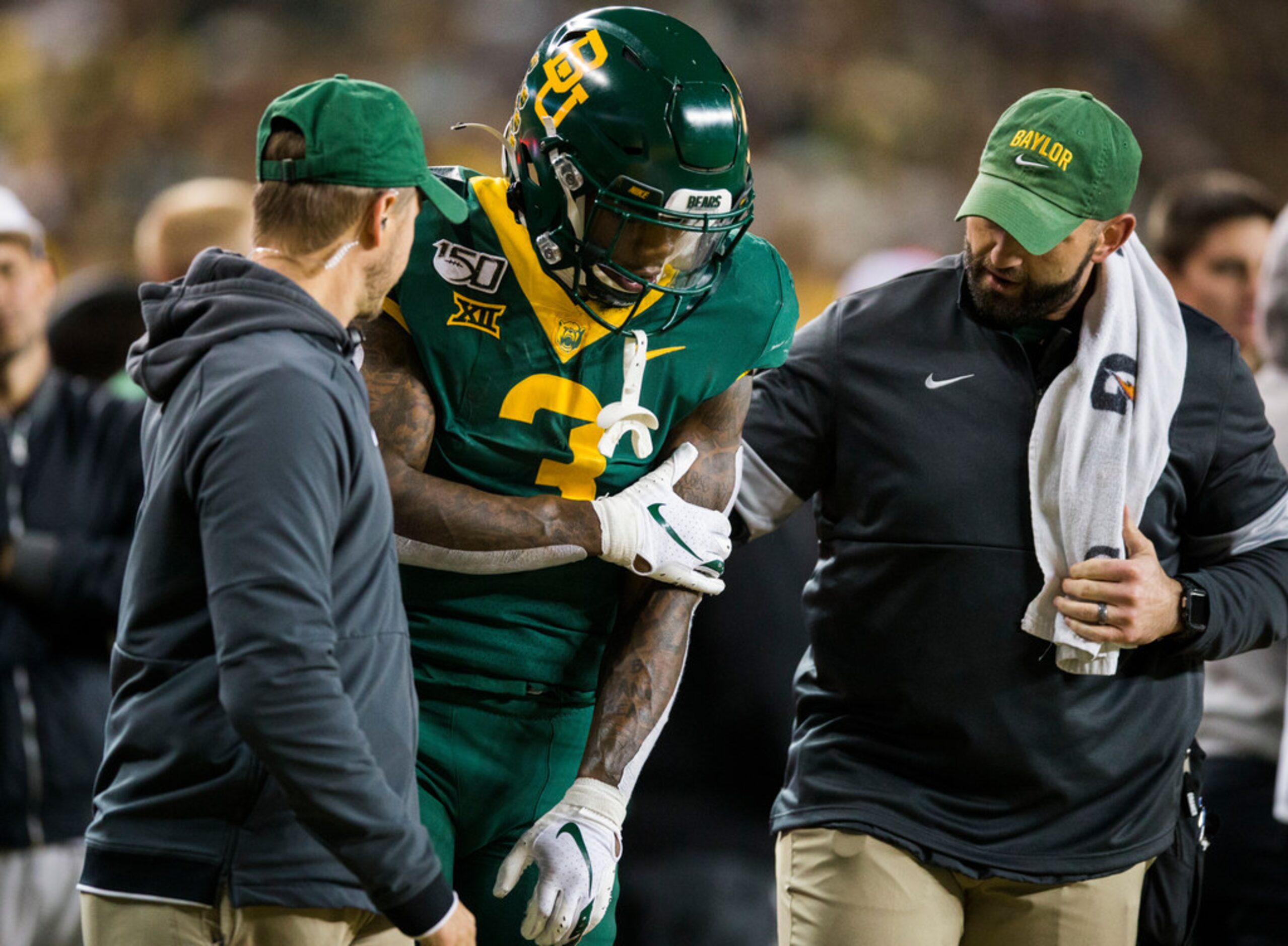 Baylor Bears safety Chris Miller (3) grabs his left arm as he's checked out during the third...