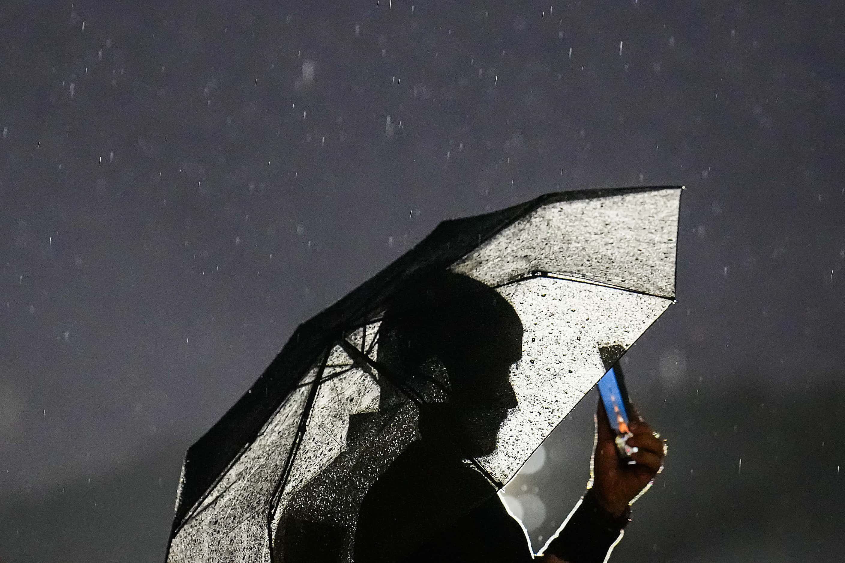A spectator watches along the Seine from under an umbrella during opening ceremonies for the...
