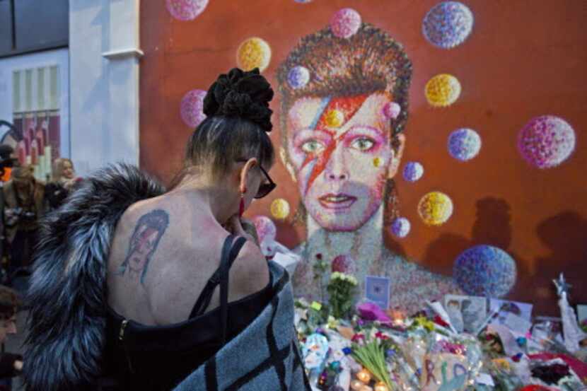 Un mujer deja una ofrenda para el músico David Bowie quien falleció el lunes, a los 69 años....