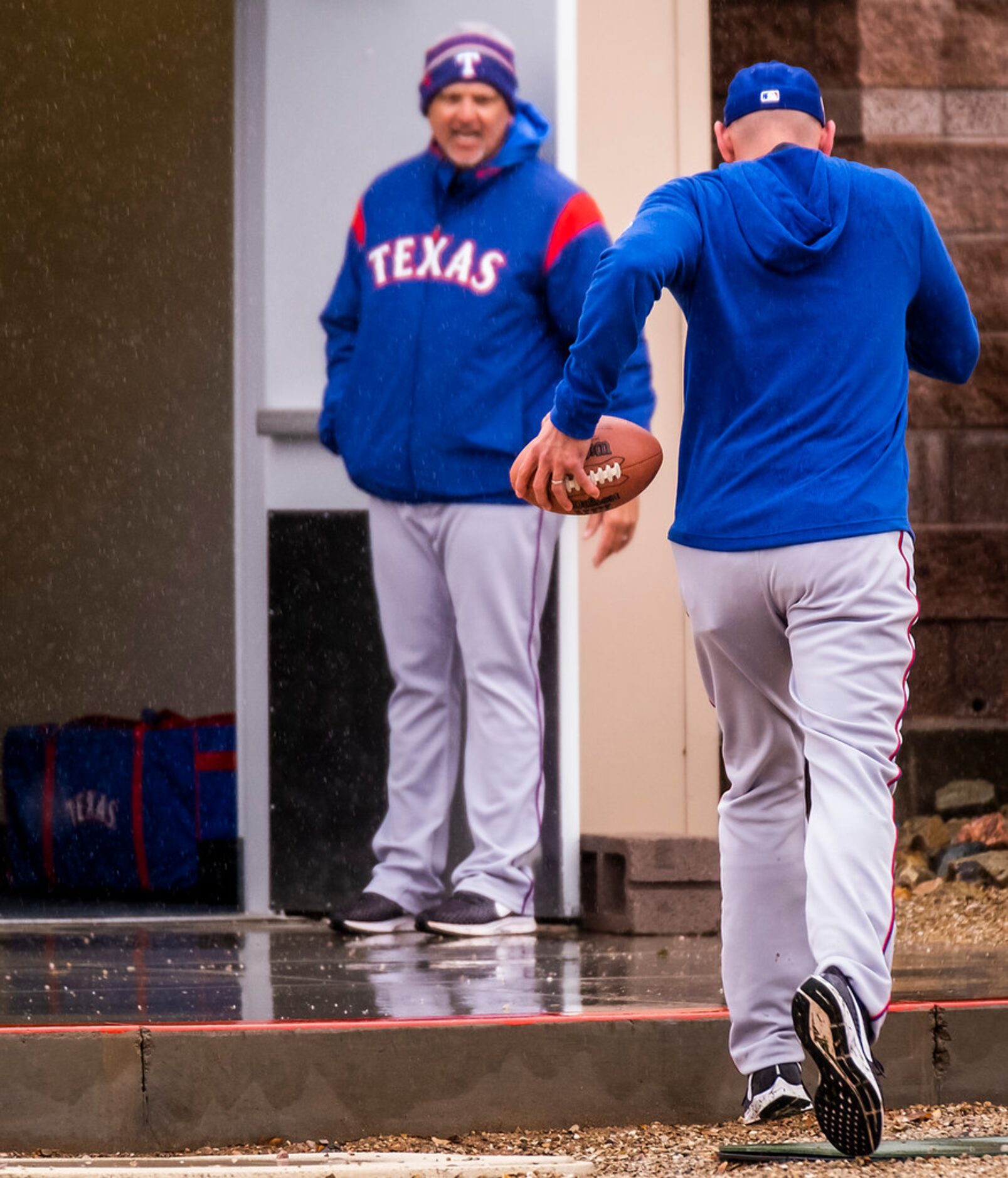 Texas Rangers first base coach Hector Ortiz holds the door open for manager Chris Woodward...