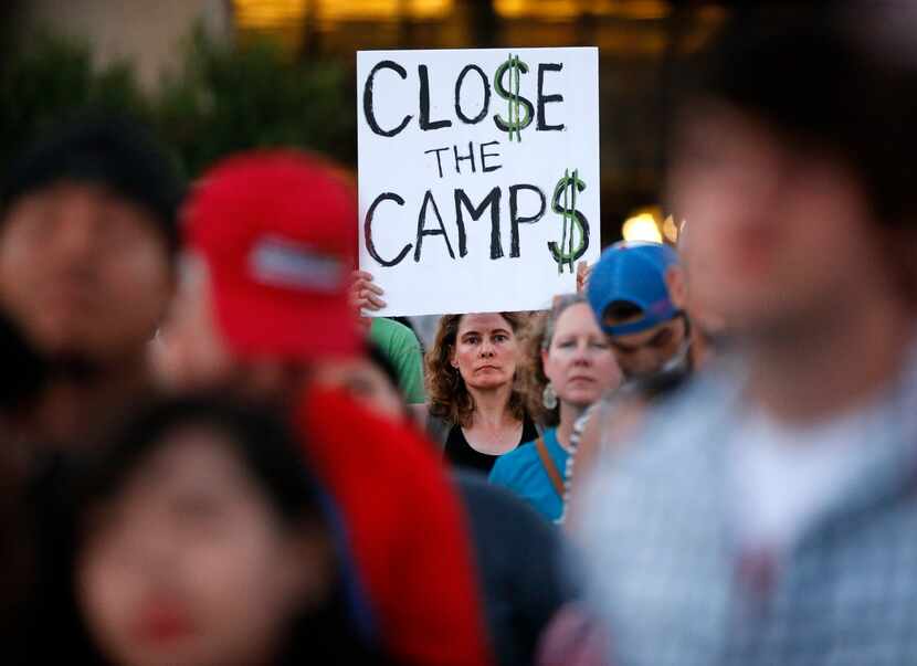 A woman holds up a "Close The Camps" sign during the Lights for Liberty candlelight vigil...