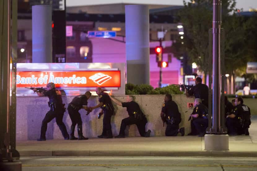 Dallas police took up positions along a wall at the corner of Lamar and Main streets, their...