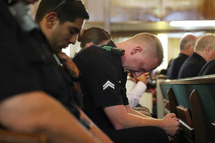Police officers from departments in and around Dallas prayed at a multicultural vigil on...