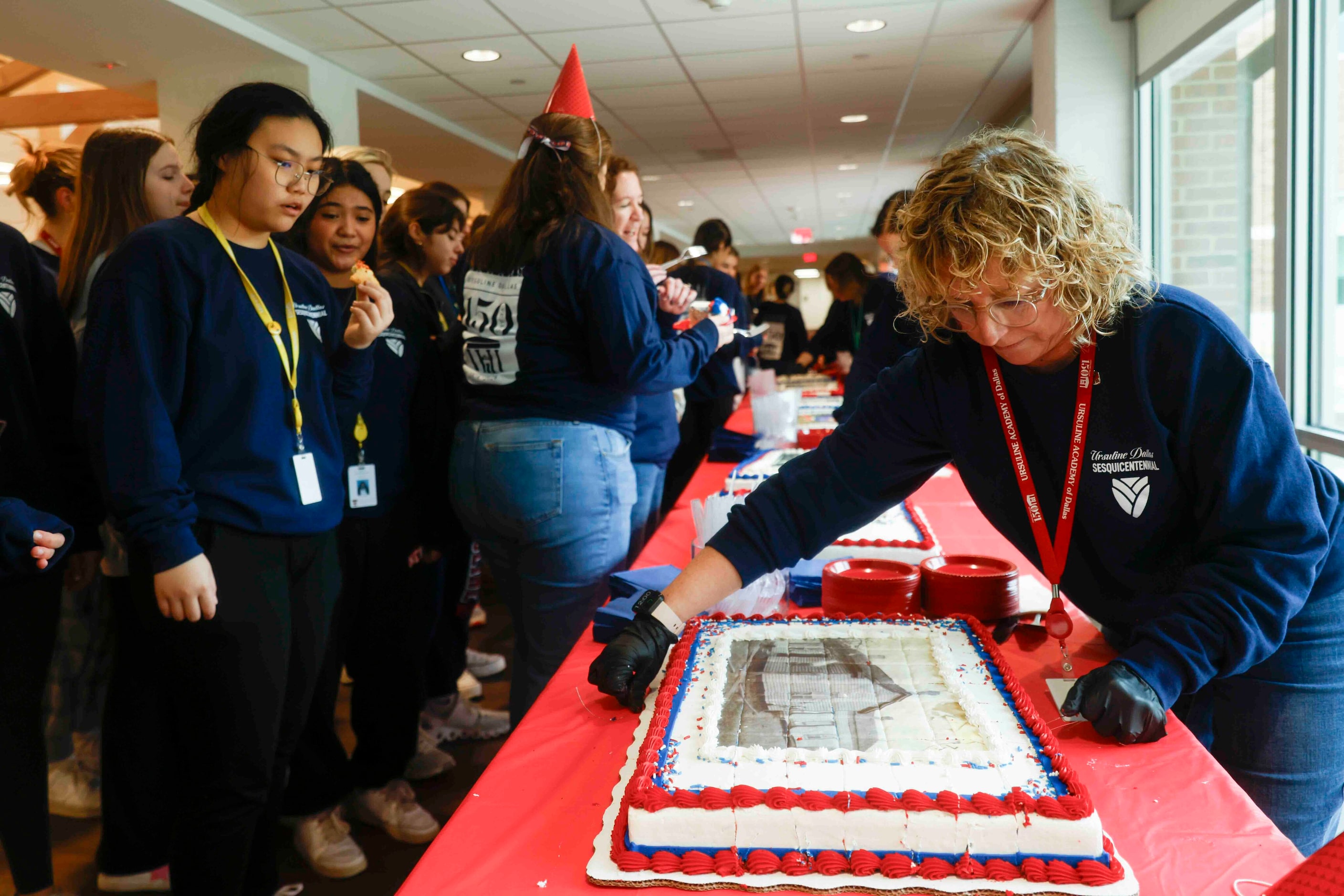 Events and Operations Manager Virginia Wallace (right) cuts the cake as students look over...