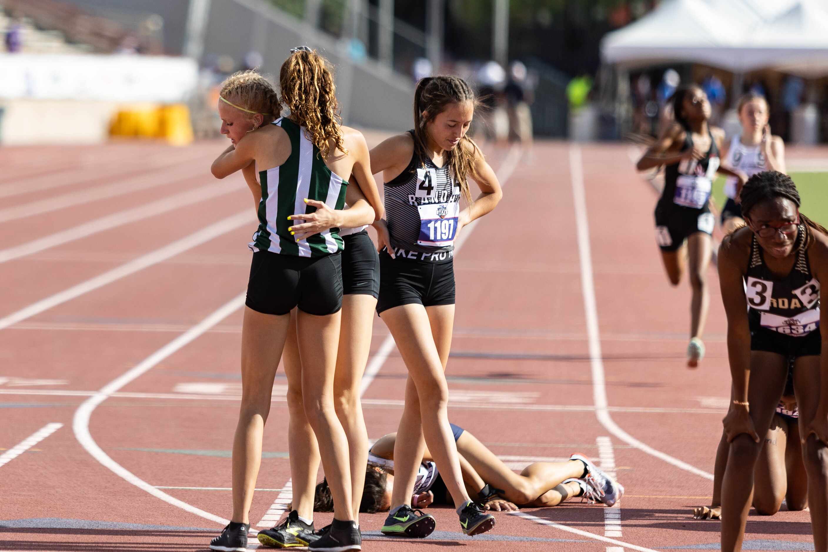 Kailey Littlefield of Lucas Lovejoy, left, hugs a competitor after winning the girls’ 800m...