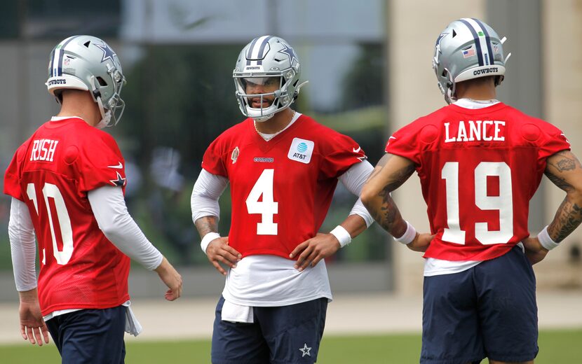 Dallas Cowboys quarterback Dak Prescott (4), center, converses with backup quarterbacks...