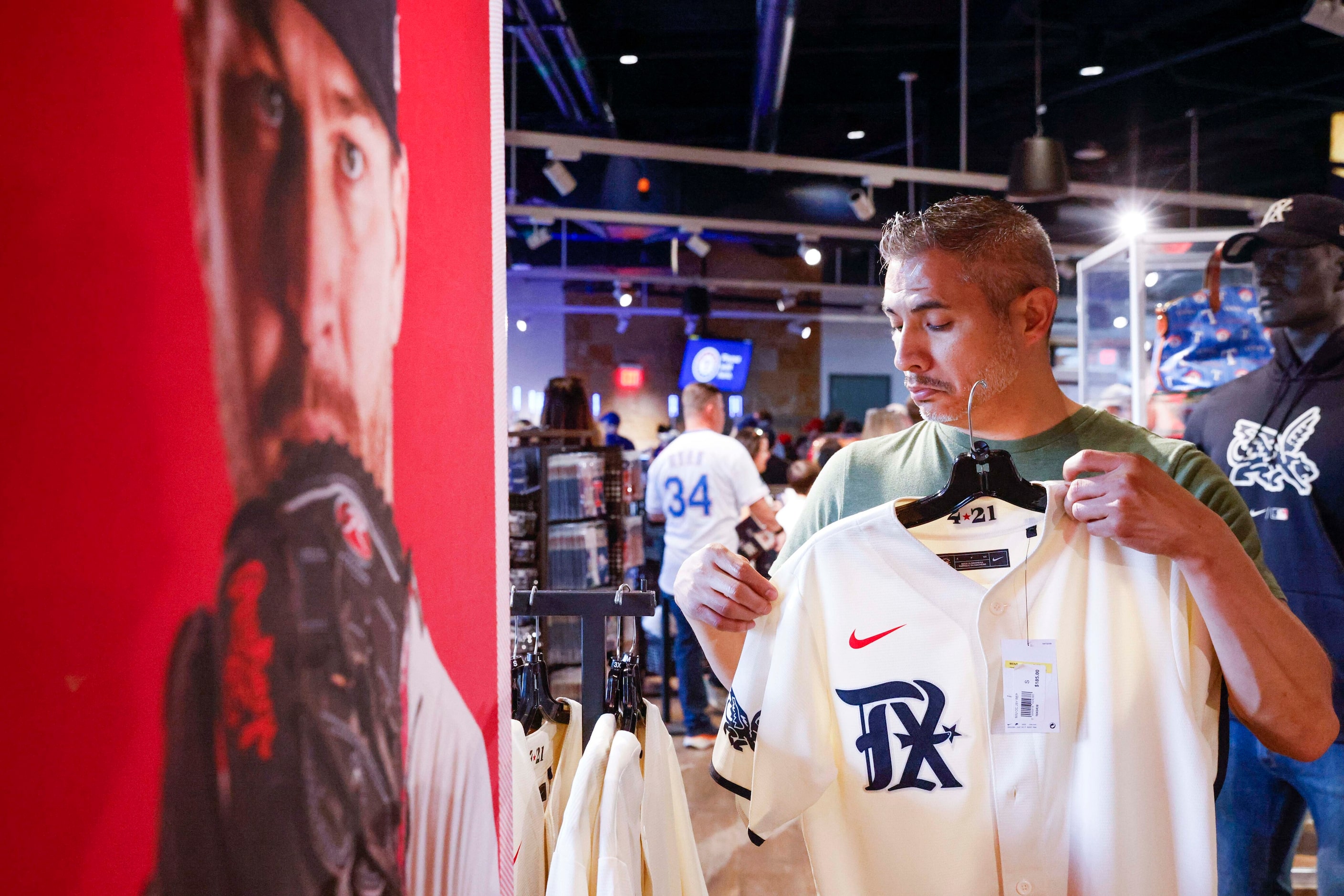 Ro Rives of Dallas area tries a Texas Rangers City Connect jersey before a baseball game...