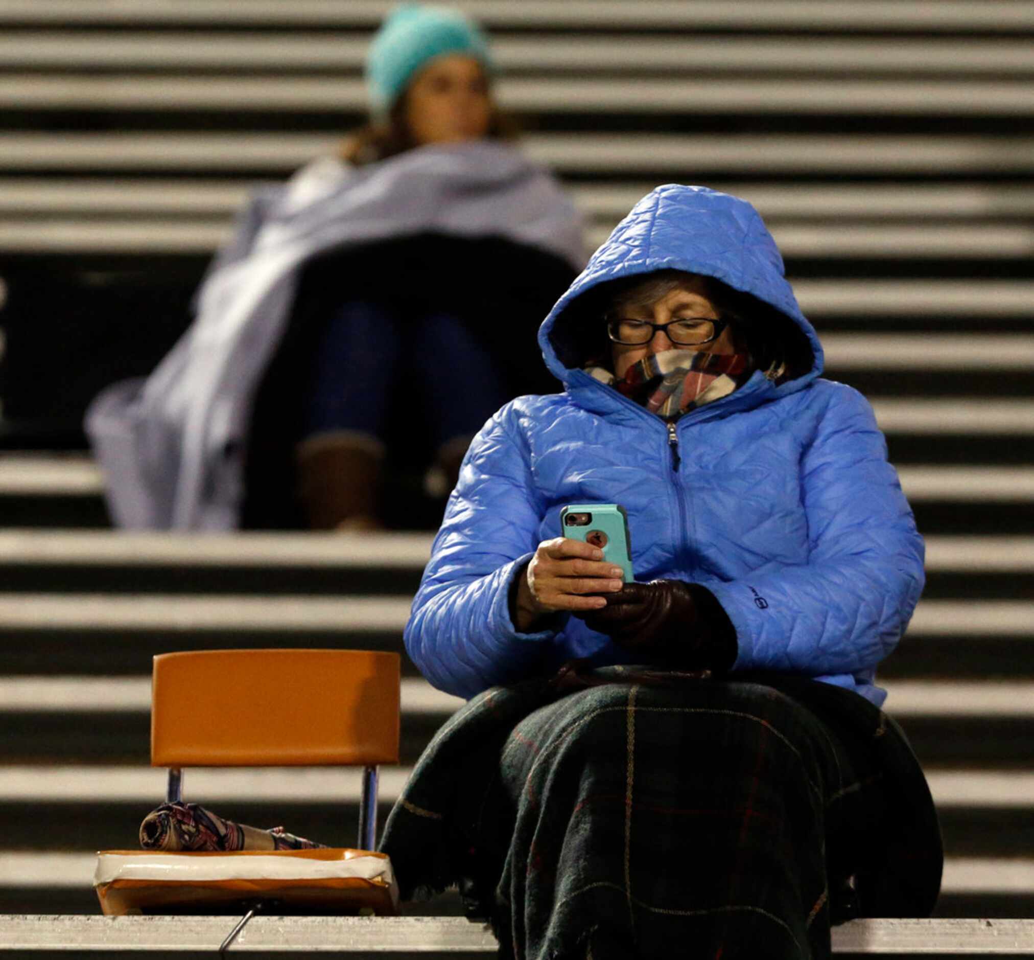 Fans in the stands bundle up against the evening chill during the first half of the...