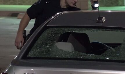 An Arlington police officer examines a vehicle in the parking lot of a fast-food restaurant...