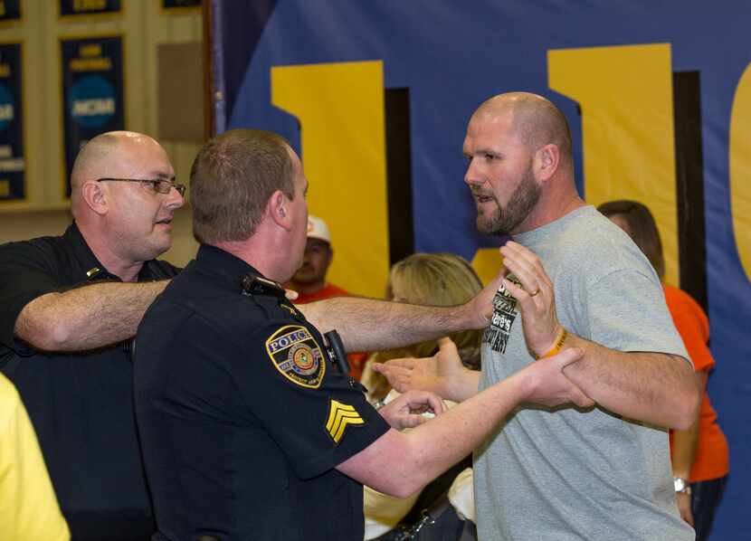 COMMERCE, TX - FEBRUARY 22: A police officer restrains a Celina fan that rushed the court...