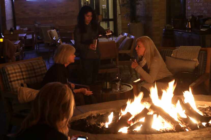 Guests enjoy drinks by the fire on the Outlaw Taproom's patio at the Four Seasons hotel in...
