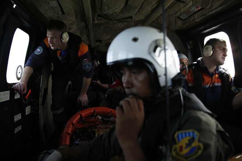 An Indonesian air force soldier (C) and Russian search team members look through the windows...
