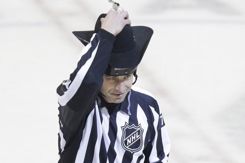 Linesman Derek Amell playfully tries on a cowboy hat that was thrown onto the ice after...