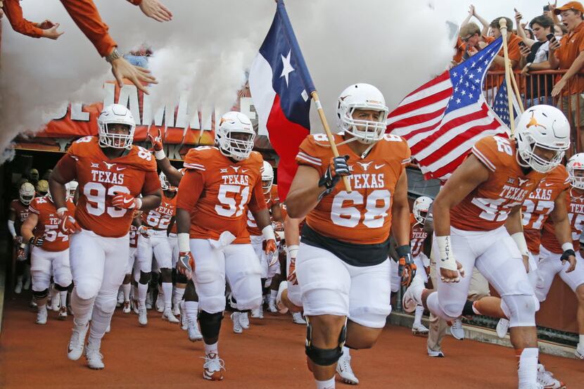 The Texas Longhorns take the field led by Texas offensive lineman Frank Lopez (68) before...