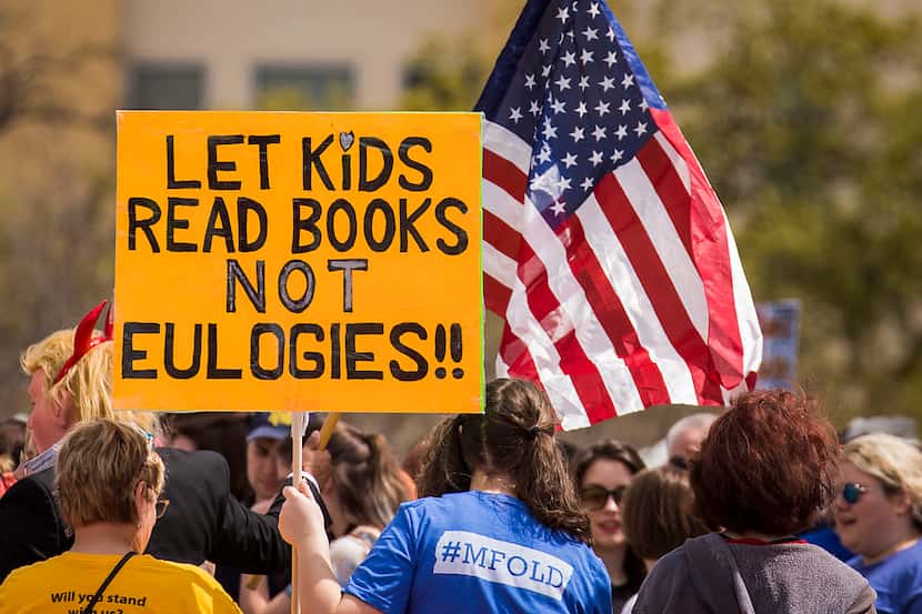 A sign reads "Let kids read books not eulogies!!" in reference to recent school shootings.