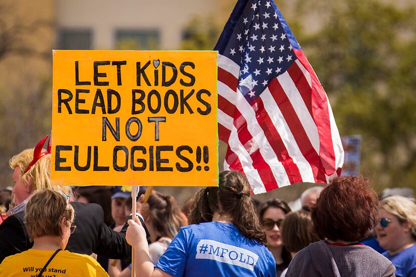 A sign reads "Let kids read books not eulogies!!" in reference to recent school shootings.