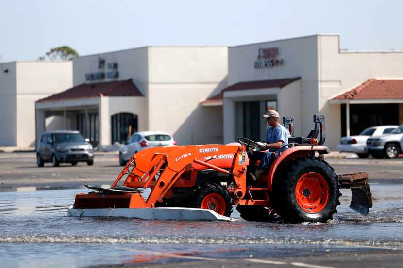 Scott Coulter from Edna moves debris across a strip mall parking lot in Rockport on...