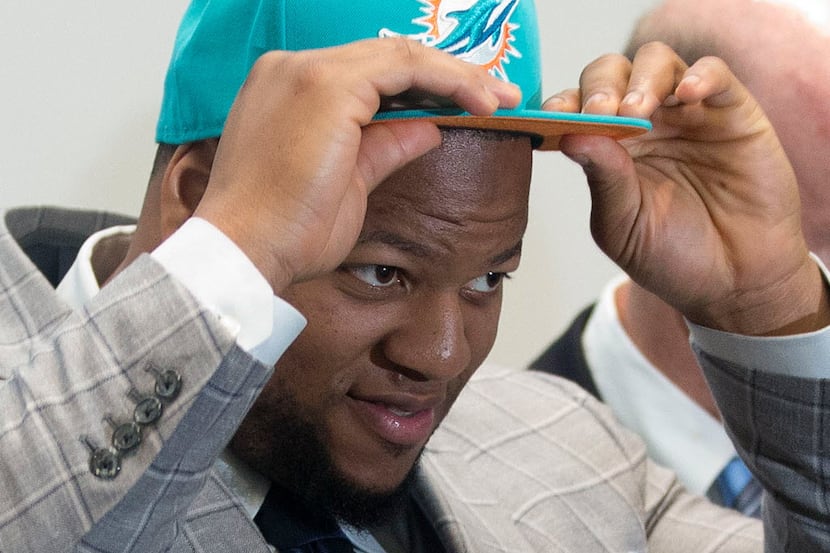 Miami Dolphins' Ndamukong Suh dons on a Dolphins cap during an NFL football news conference...