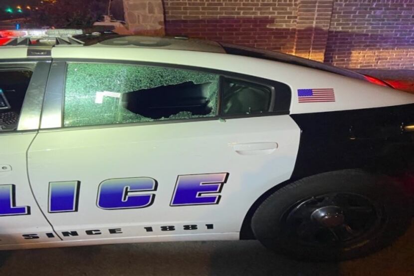 Dallas police are searching for a suspect who shot at a squad car, smashing the rear...