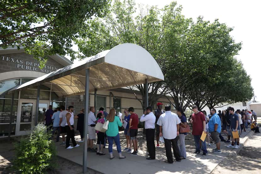 Decenas de personas hacen fila en las afueras de un centro de procesamiento de licencias en...