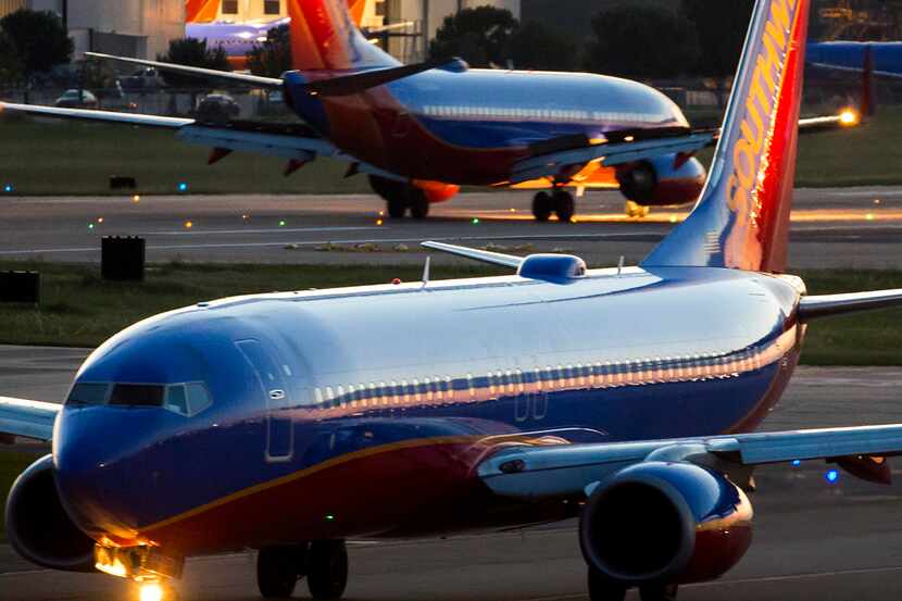 Southwest Airlines 737 planes taxi in opposite directions near a maintenance hangar at Love...