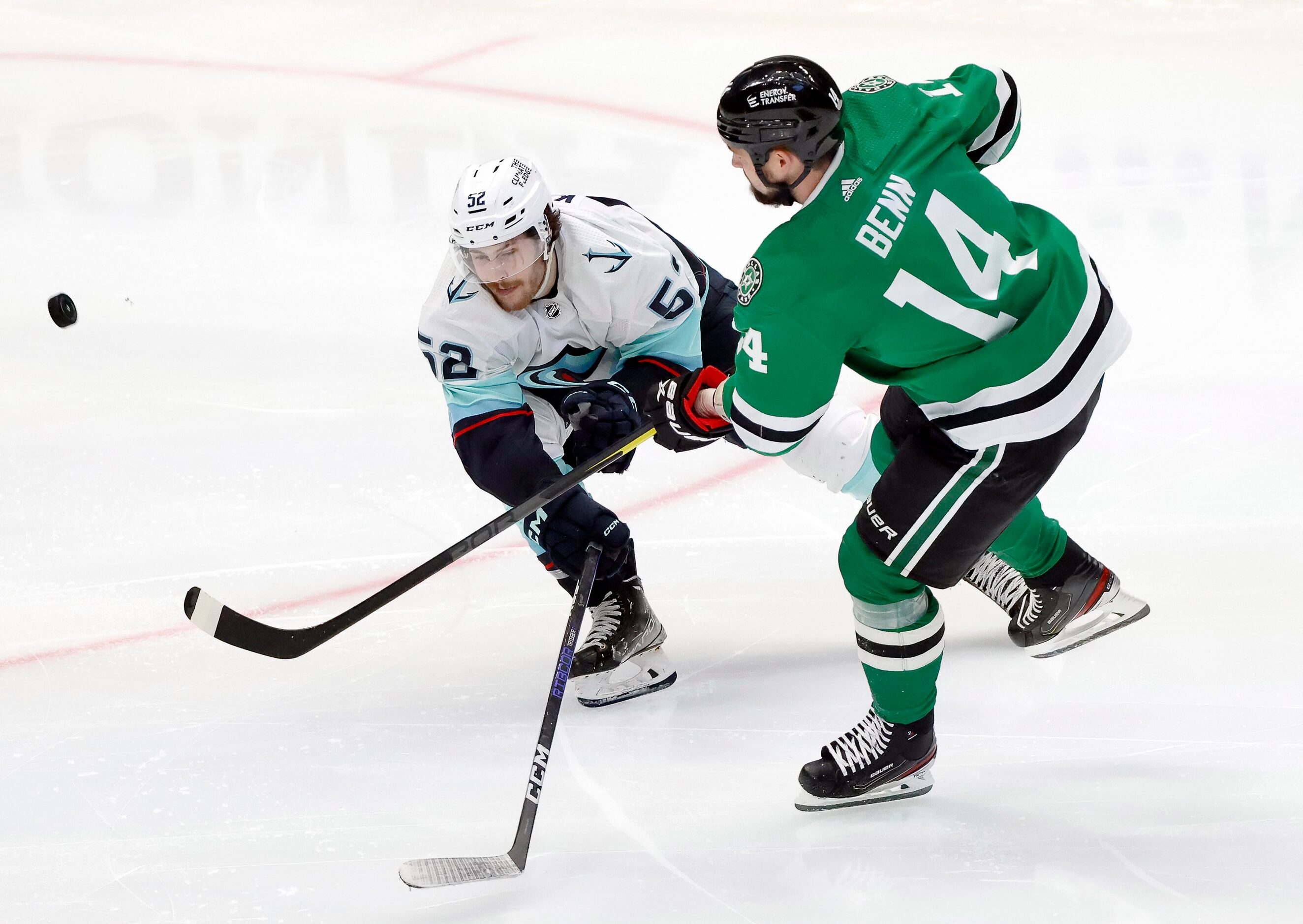 Dallas Stars left wing Jamie Benn (14) attempts a shot as he’s hacked by Seattle Kraken left...