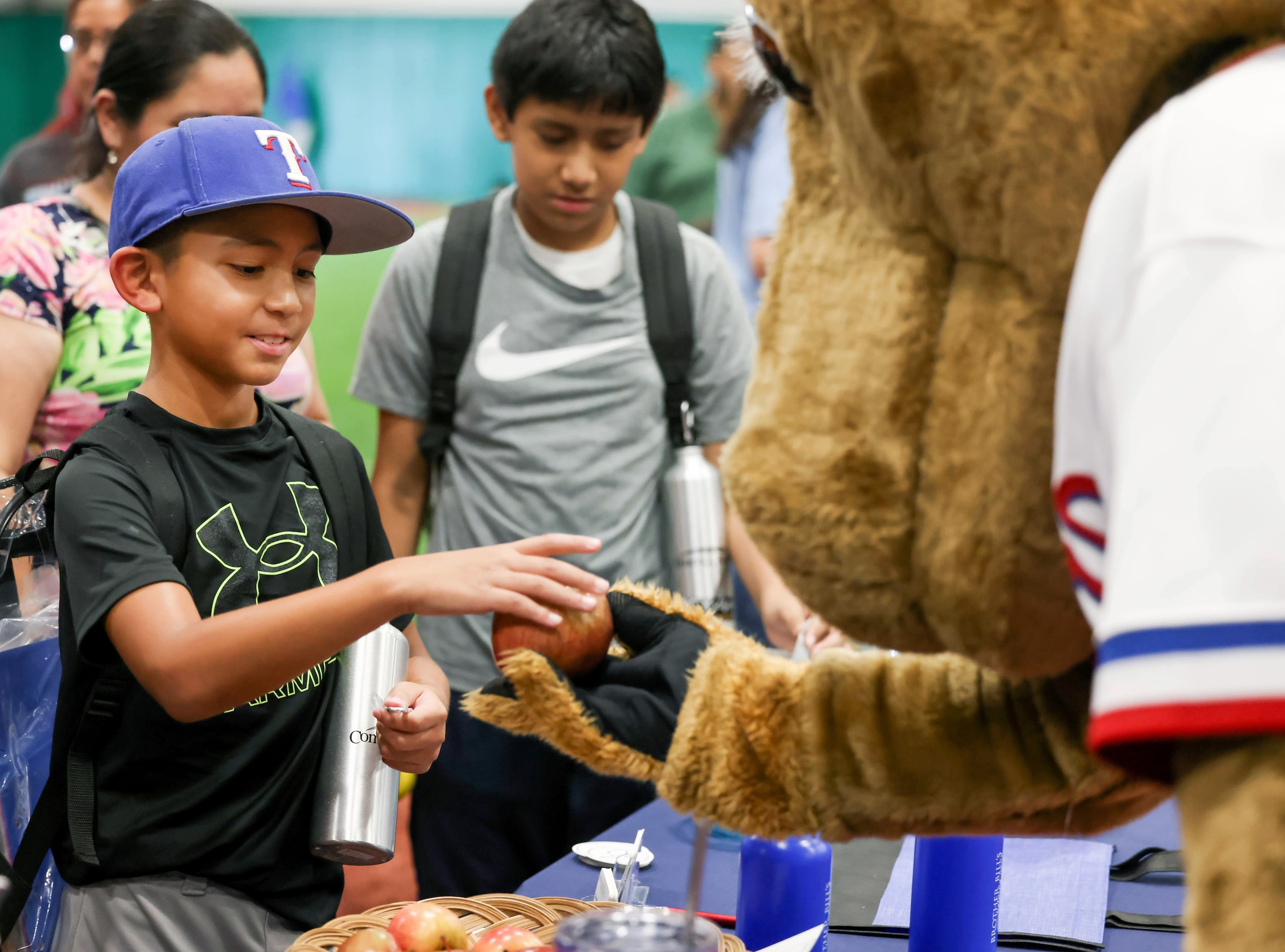 Joseph Tonches (left), 8, takes an apple from Texas Rangers mascot Captain at a...