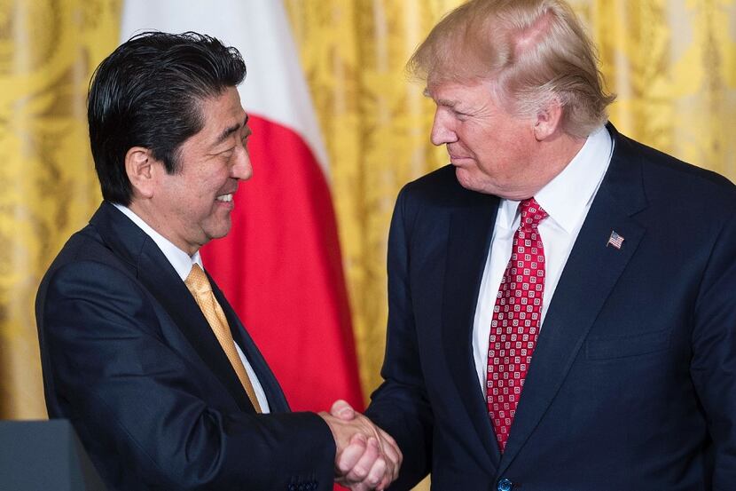 TOPSHOT - Japan's Prime Minister Shinzo Abe (L) and US President Donald Trump shake hands...