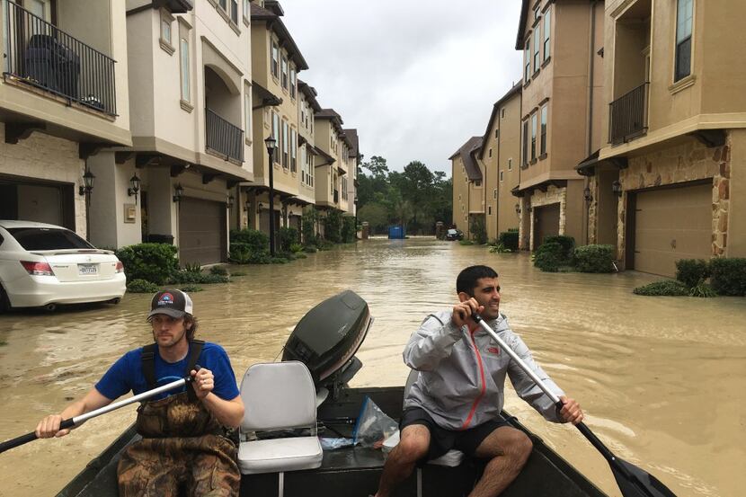 Dallas residents Josh Womack and Sammy Abdullah paddle through a row of townhomes on a...
