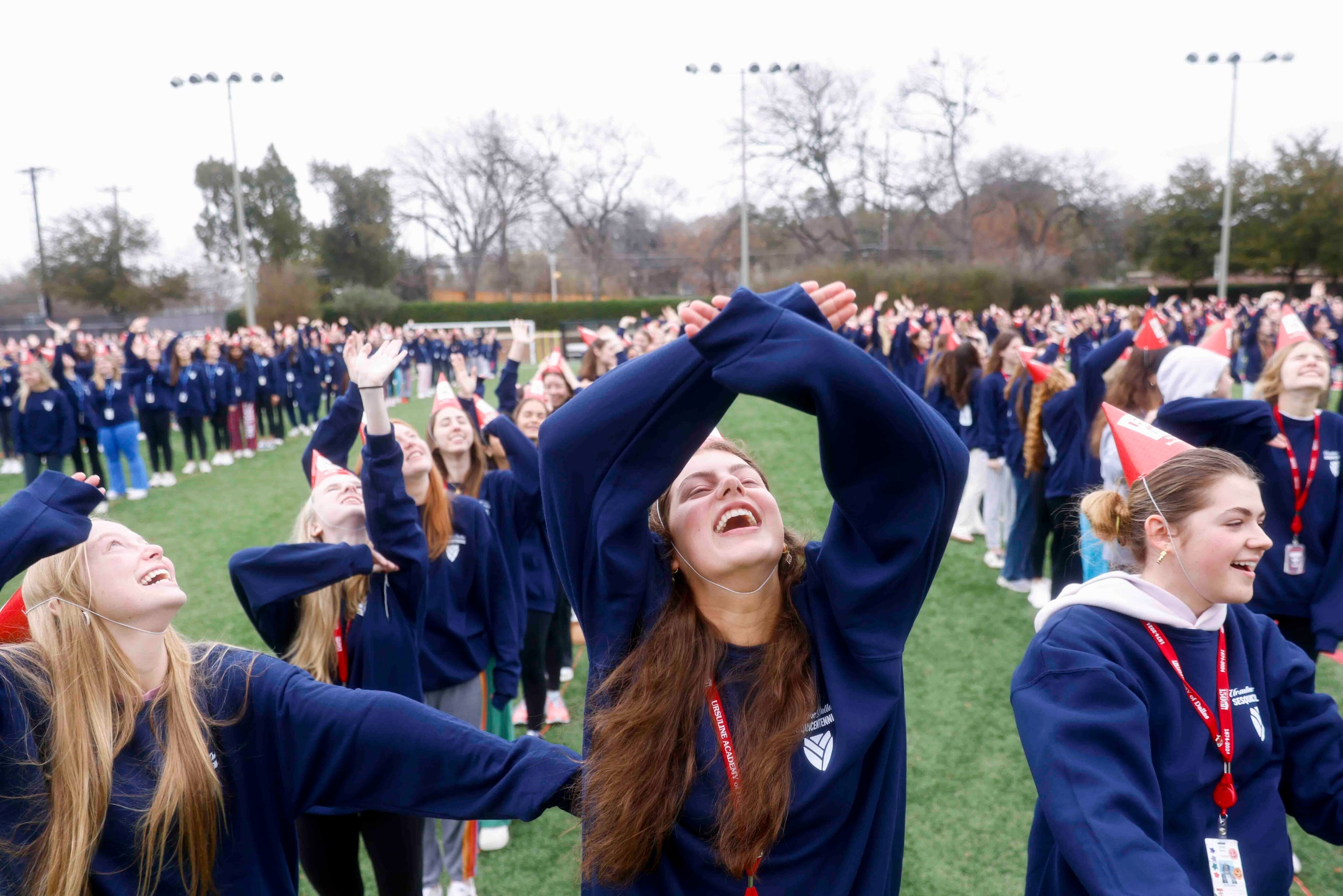 From left, dtudents Maddox Johnson, Eloise Love, and Trinity Richey cheer while standing for...