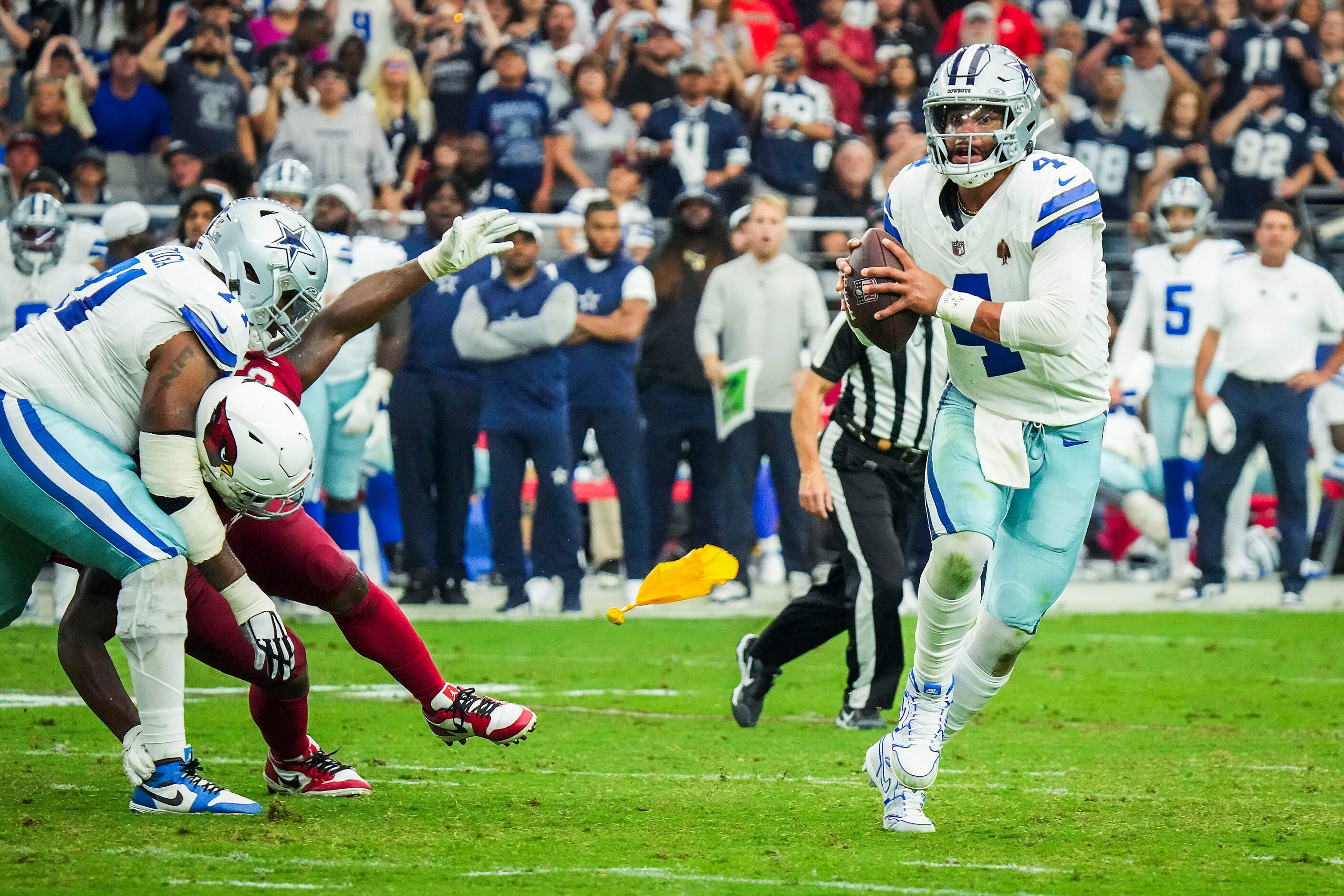 Dallas Cowboys quarterback Dak Prescott scrambles from the pocket as a flag flies to...