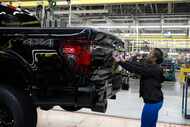 Assembly line worker Lashunta Harris applies the Ford logo on a 2024 Ford F-150 truck being...