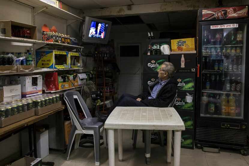 An Israeli grocery store owner watches  the US Secretary of State John Kerry speech at the...