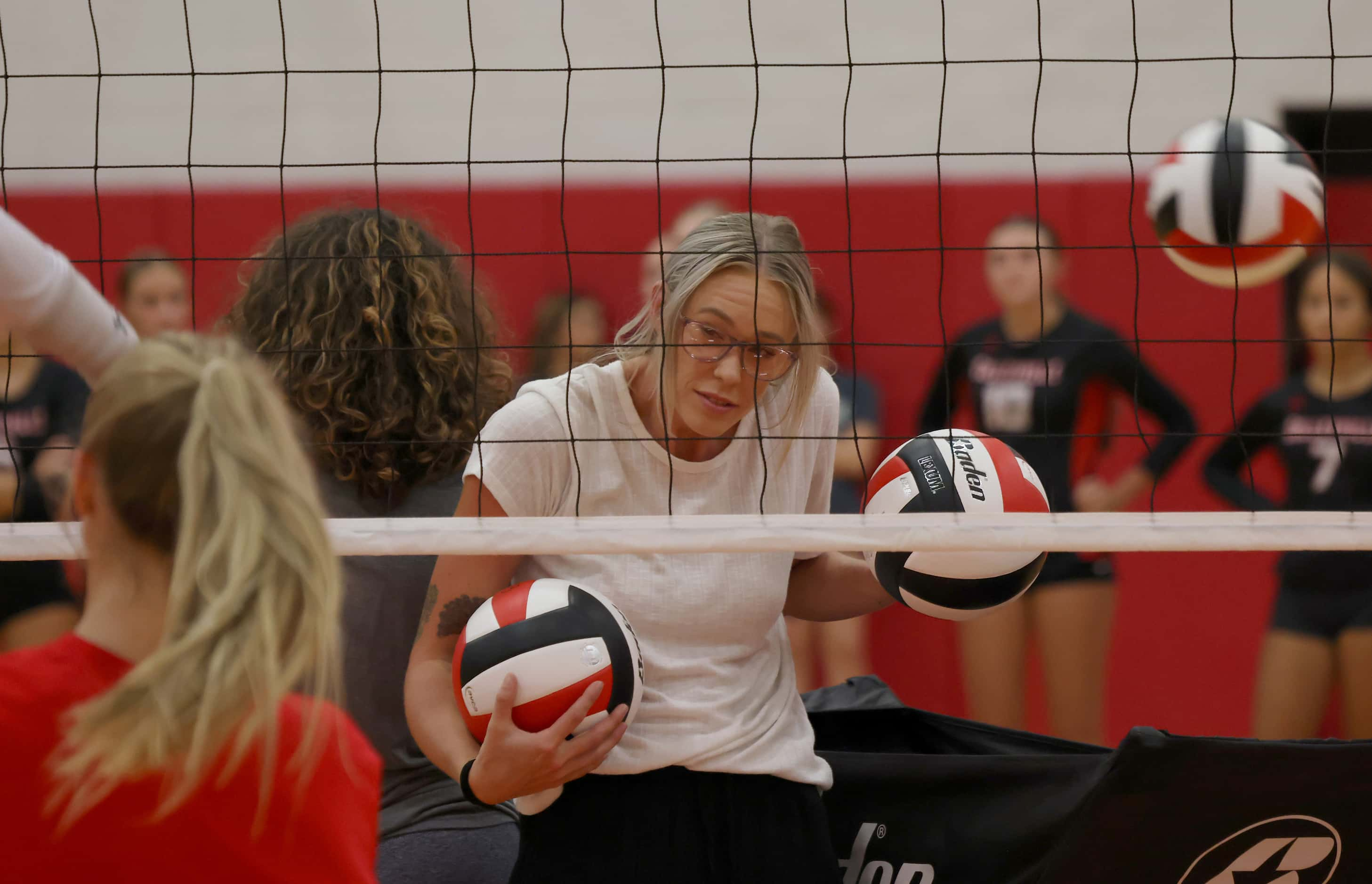 Colleyville Heritage assistant volleyball coach Olivia Burnett winces as she ducks to avoid...