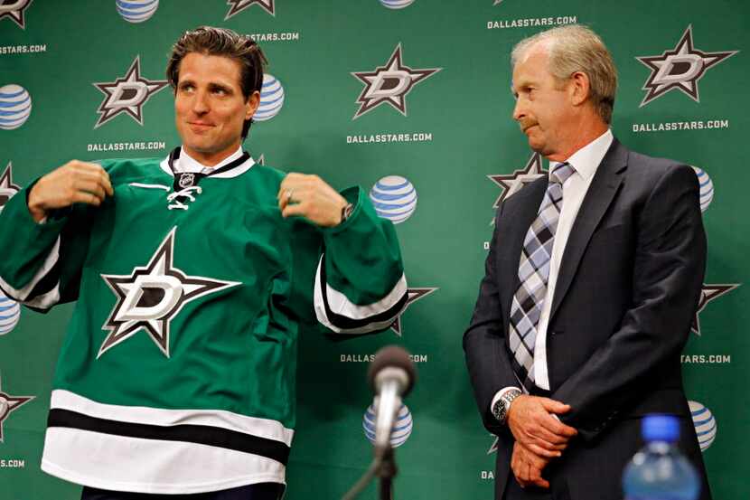 New Dallas Stars wing Patrick Sharp (left) dons the team jersey as general manager Jim Nill...