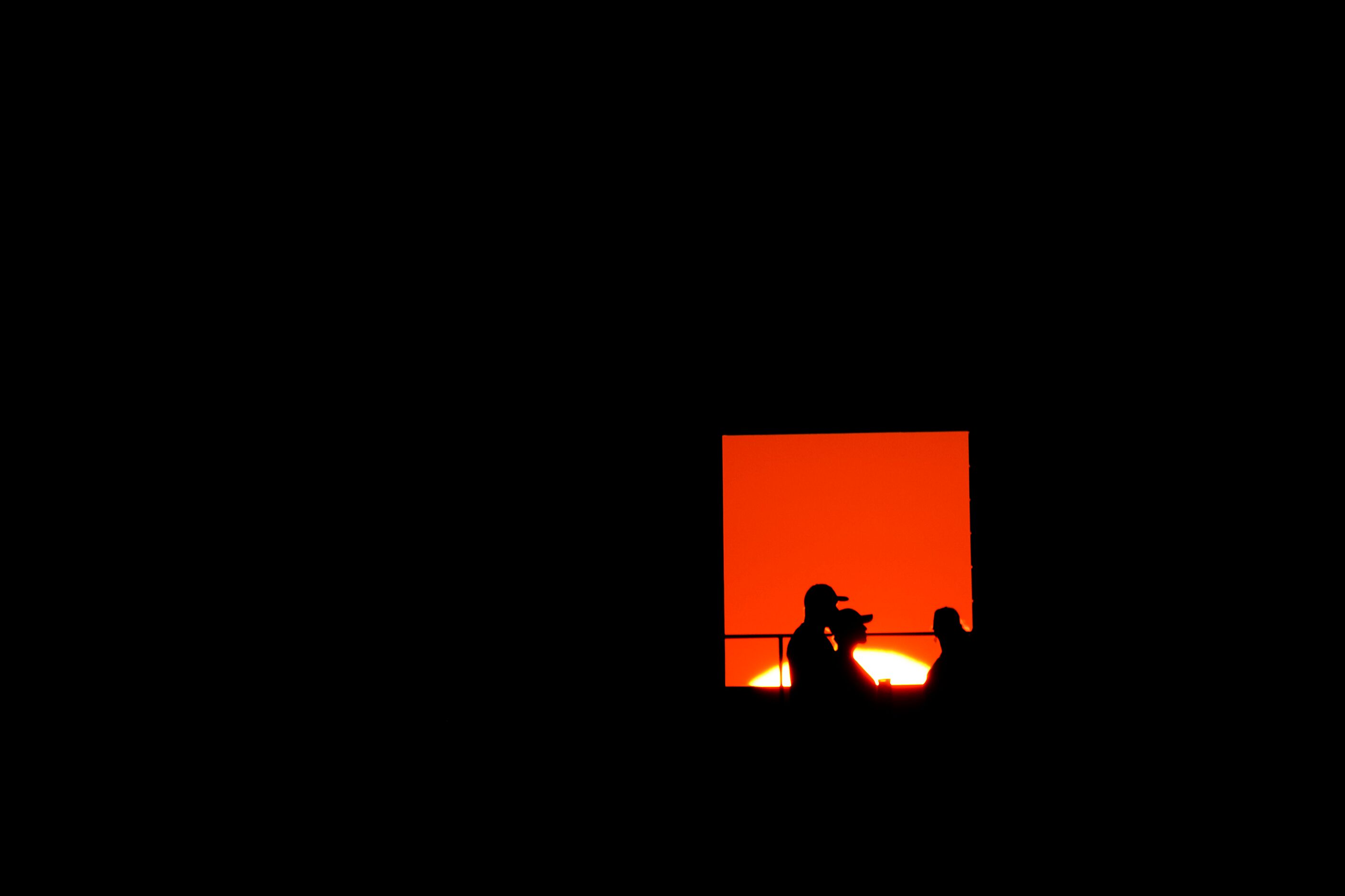 The setting sun is seen through an opening as fans walk on the upper deck at Globe Life Park...