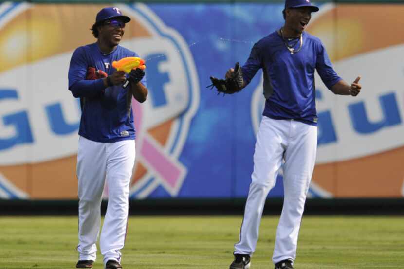 Neftali Feliz, left, sprays Alexi Ogando with a water gun during batting practice before a...