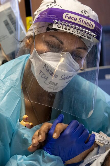 Nurse Natalie Salazar held the hand of an intubated COVID-19 patient in the Tactical Care...