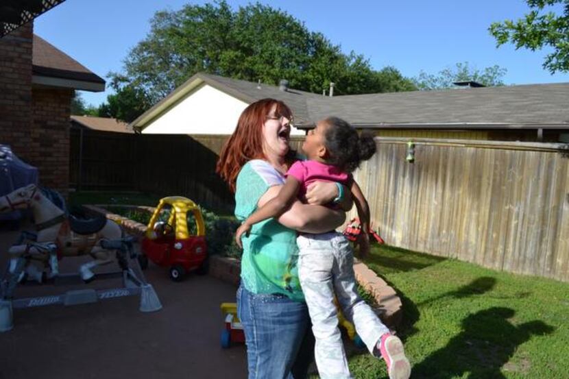
Kimmy picks up her 4-year-old daughter for a kiss while playing in the backyard before...