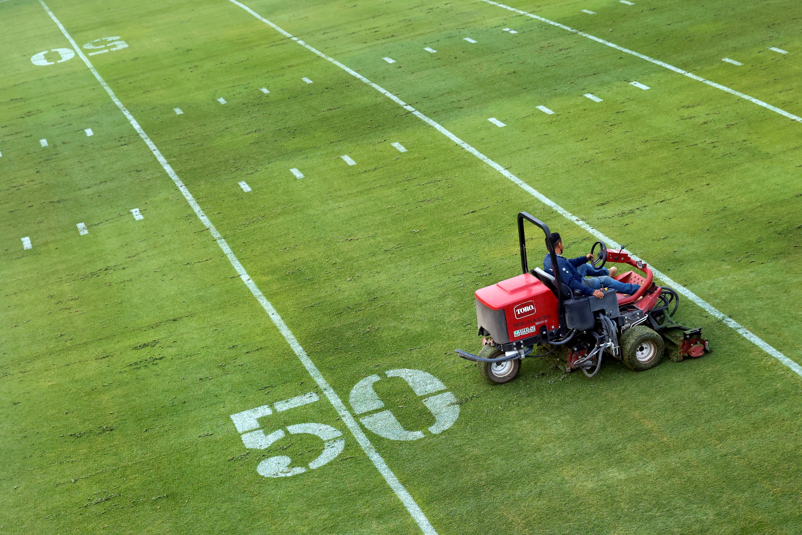 Grounds crewman Alberto Ortega cuts the grass fields in preparation for the Dallas Cowboys...