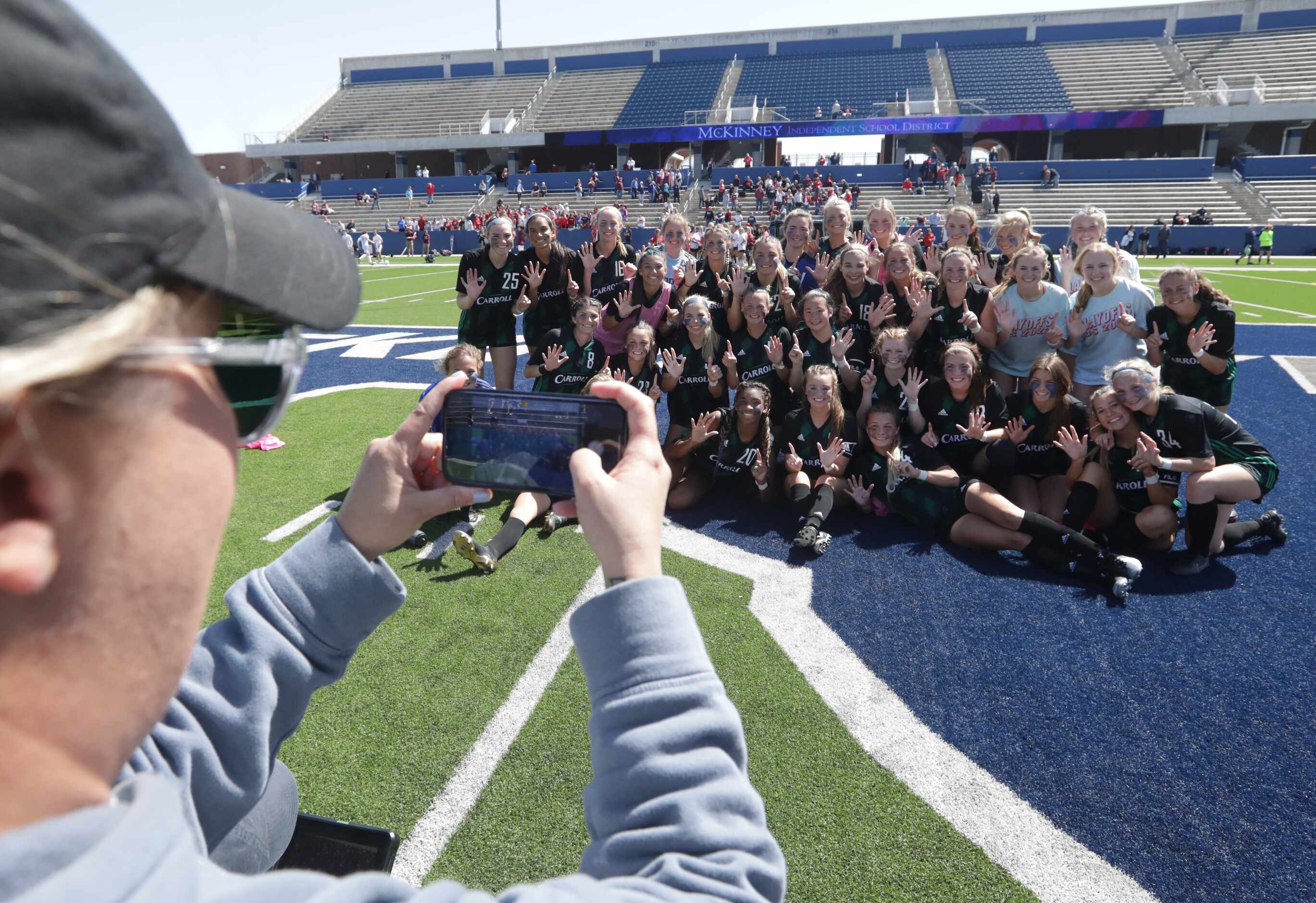 Assistant coach Lindsey Jacobson takes a photo of the Southlake Carroll players as they...